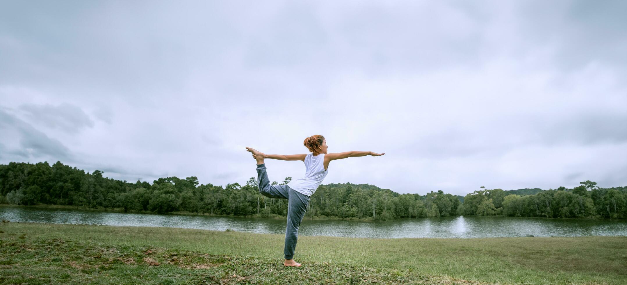 Asian women relax in the holiday. Play if yoga. on a green pasture. photo