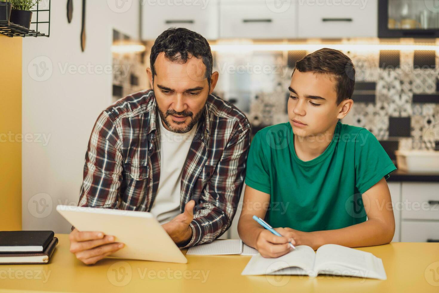 Father is helping his son with learning. They are doing homework together. photo