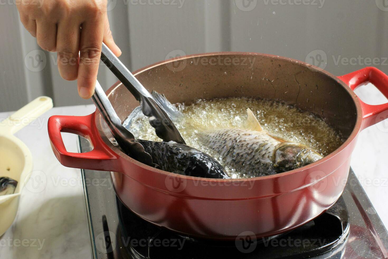 Process of Frying River Carp Fish in a Red Frying Pan. photo