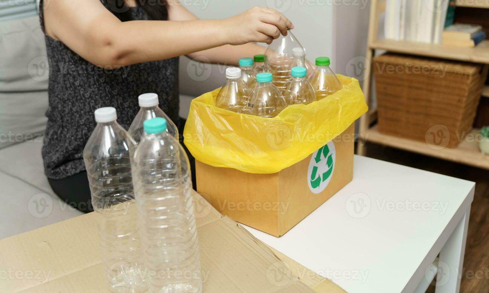 Home recycle eco green zero concept Woman throwing empty plastic bottle in recycling bin with yellow garbage bags at home. photo