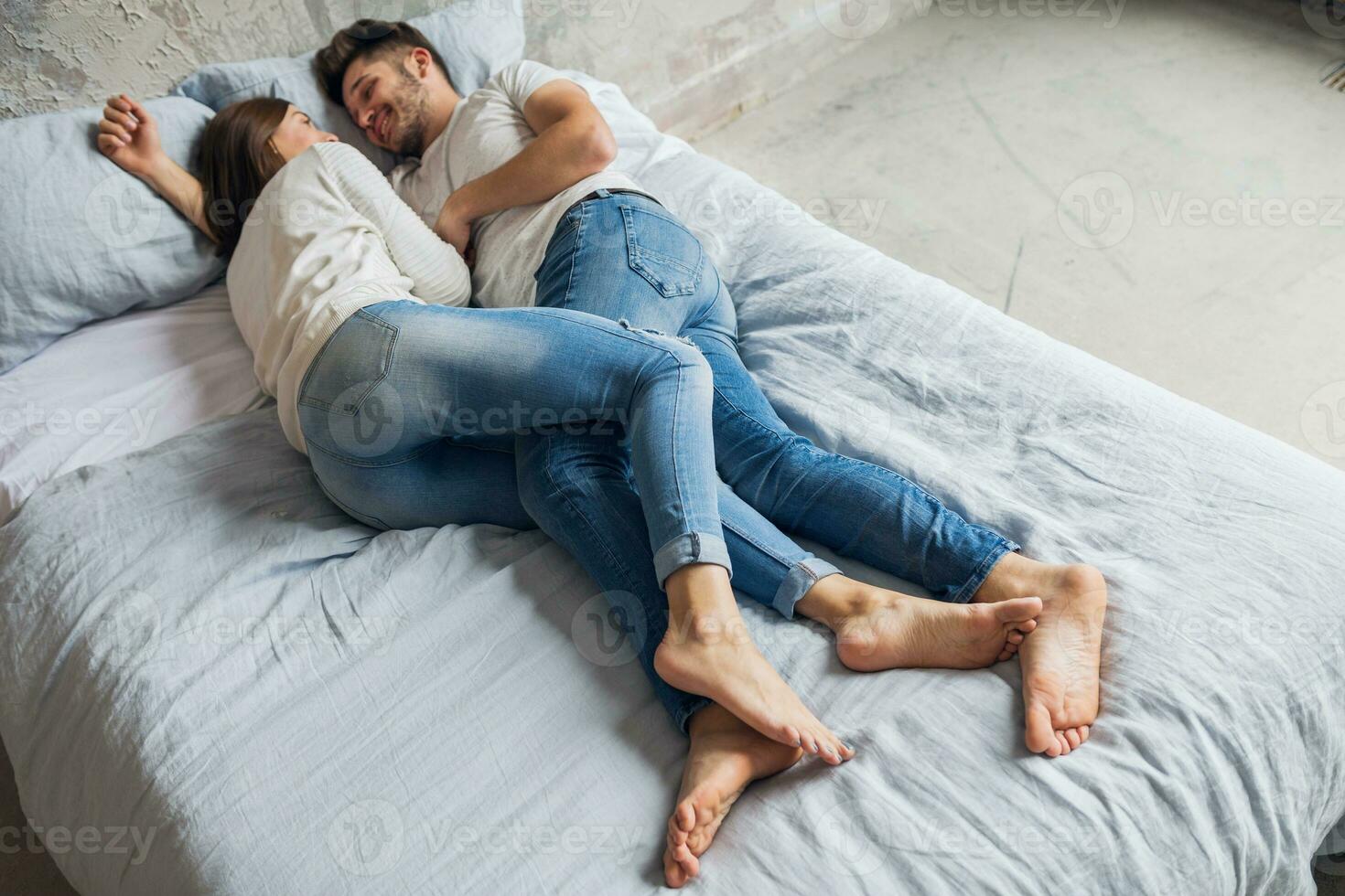 young happy smiling couple sitting on bed at home photo