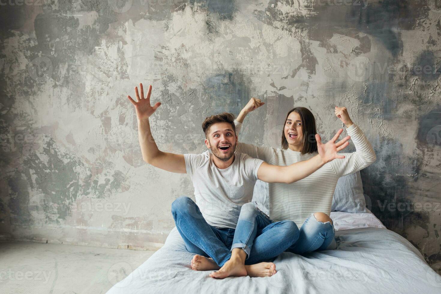 young happy smiling couple sitting on bed at home photo