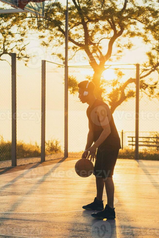negro hombre haciendo Deportes, jugando baloncesto en amanecer, activo estilo de vida, soleado verano Mañana foto