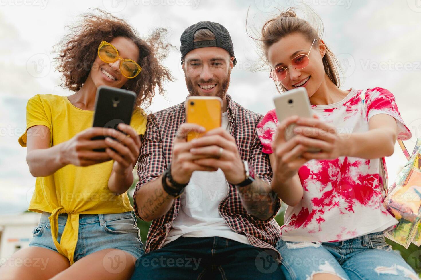 happy young company of smiling friends sitting in park photo