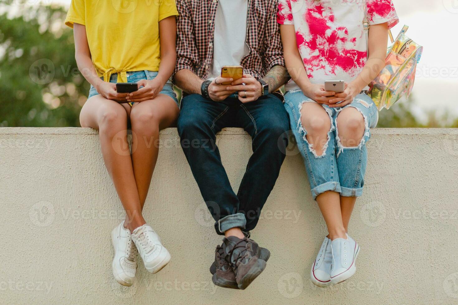 happy young company of smiling friends sitting in park photo