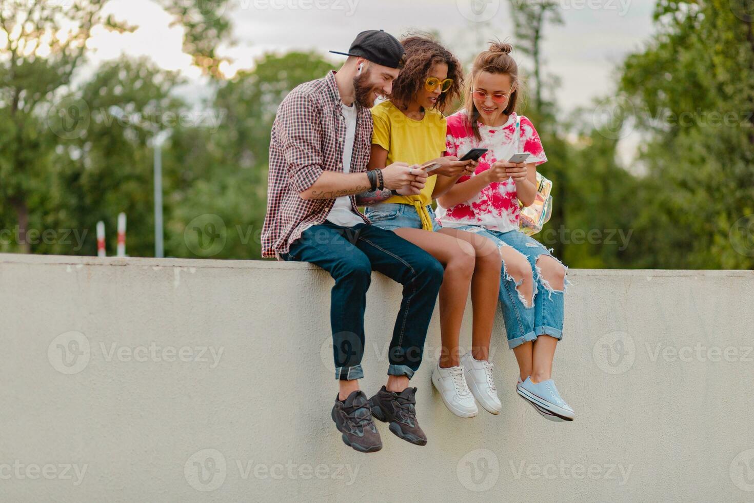 happy young company of smiling friends sitting in park photo