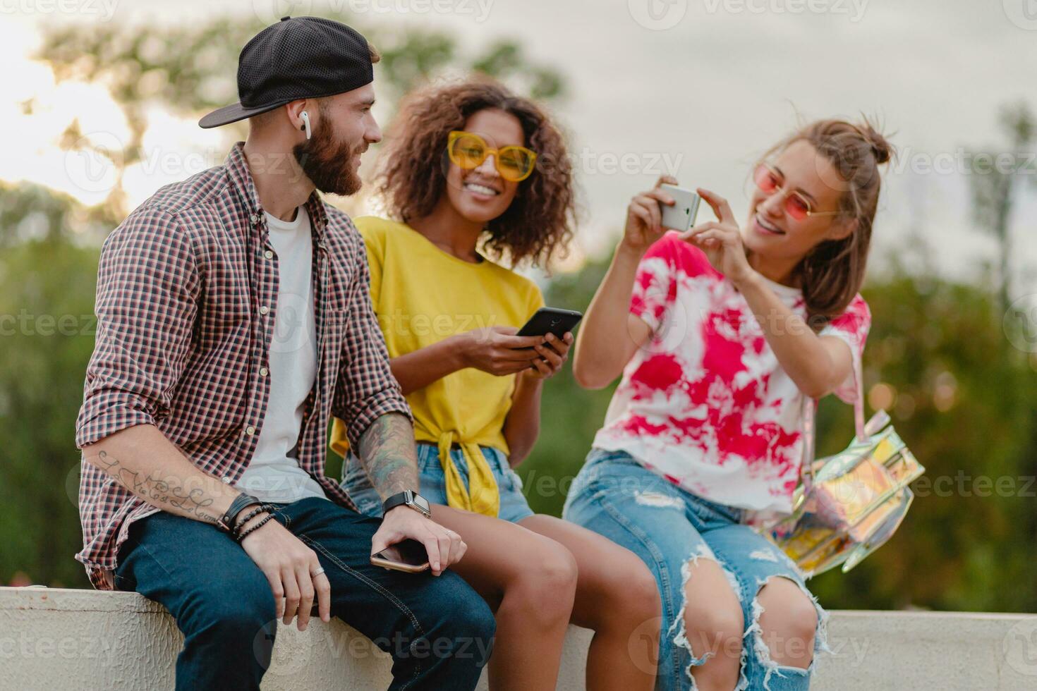 happy young company of smiling friends sitting in park photo