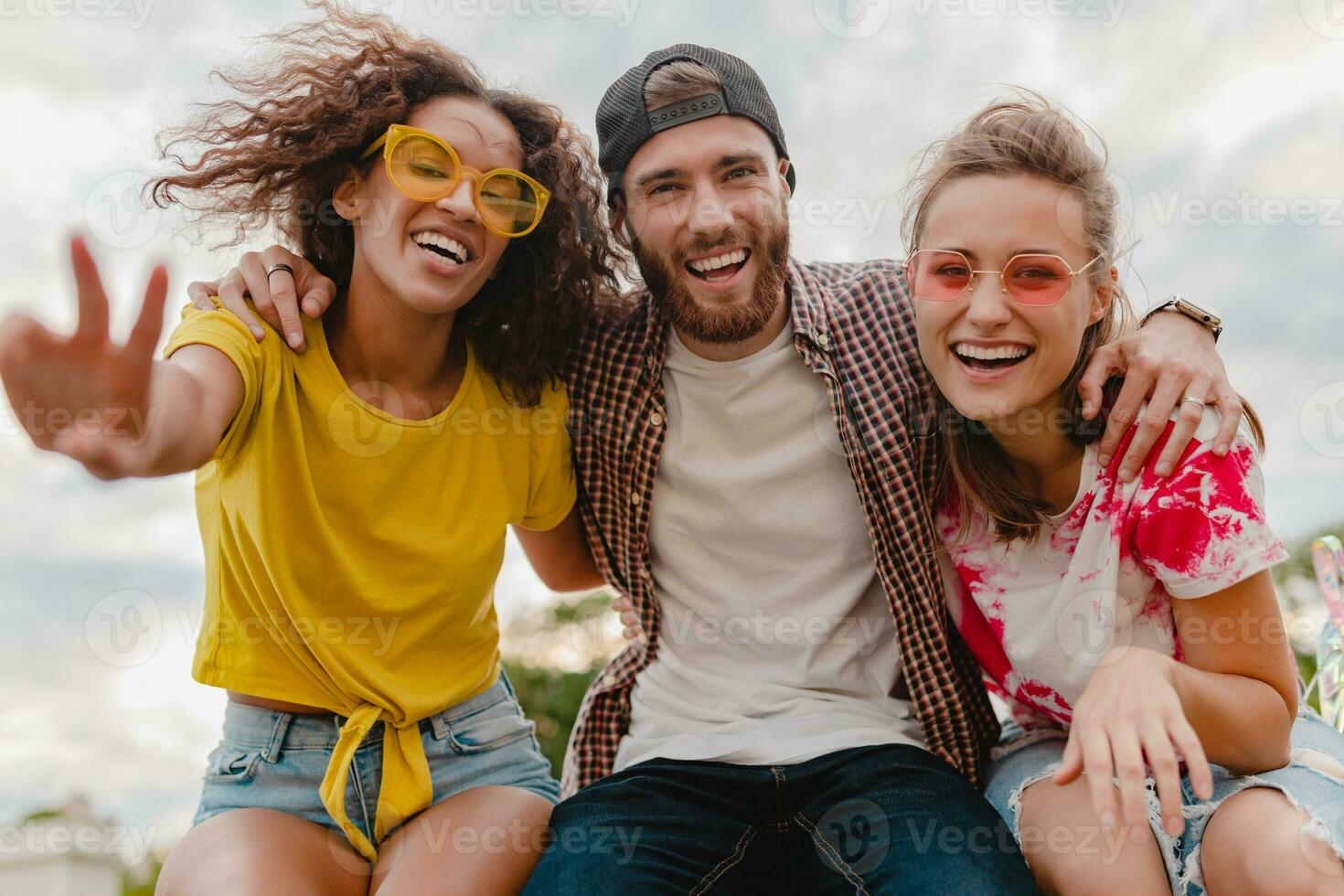 happy young company of smiling friends sitting in park photo