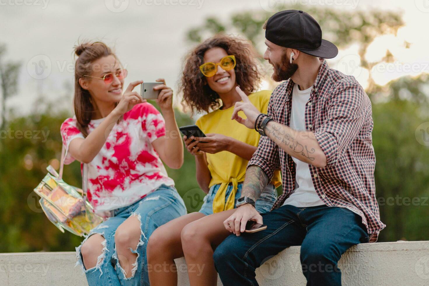 happy young company of smiling friends sitting in park photo