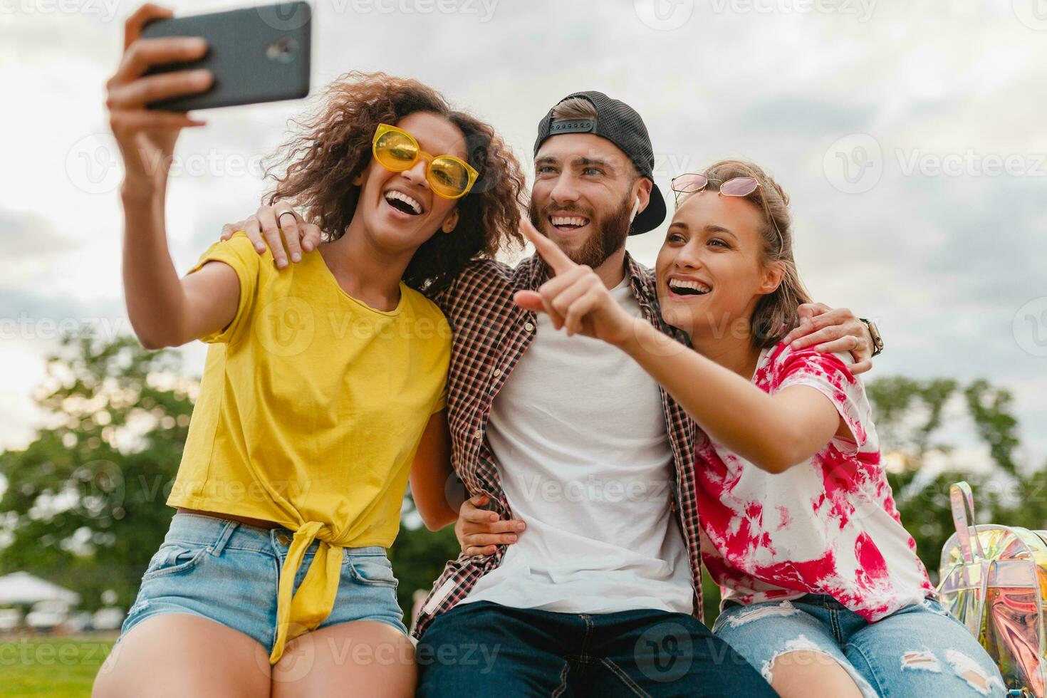 happy young company of smiling friends sitting in park photo