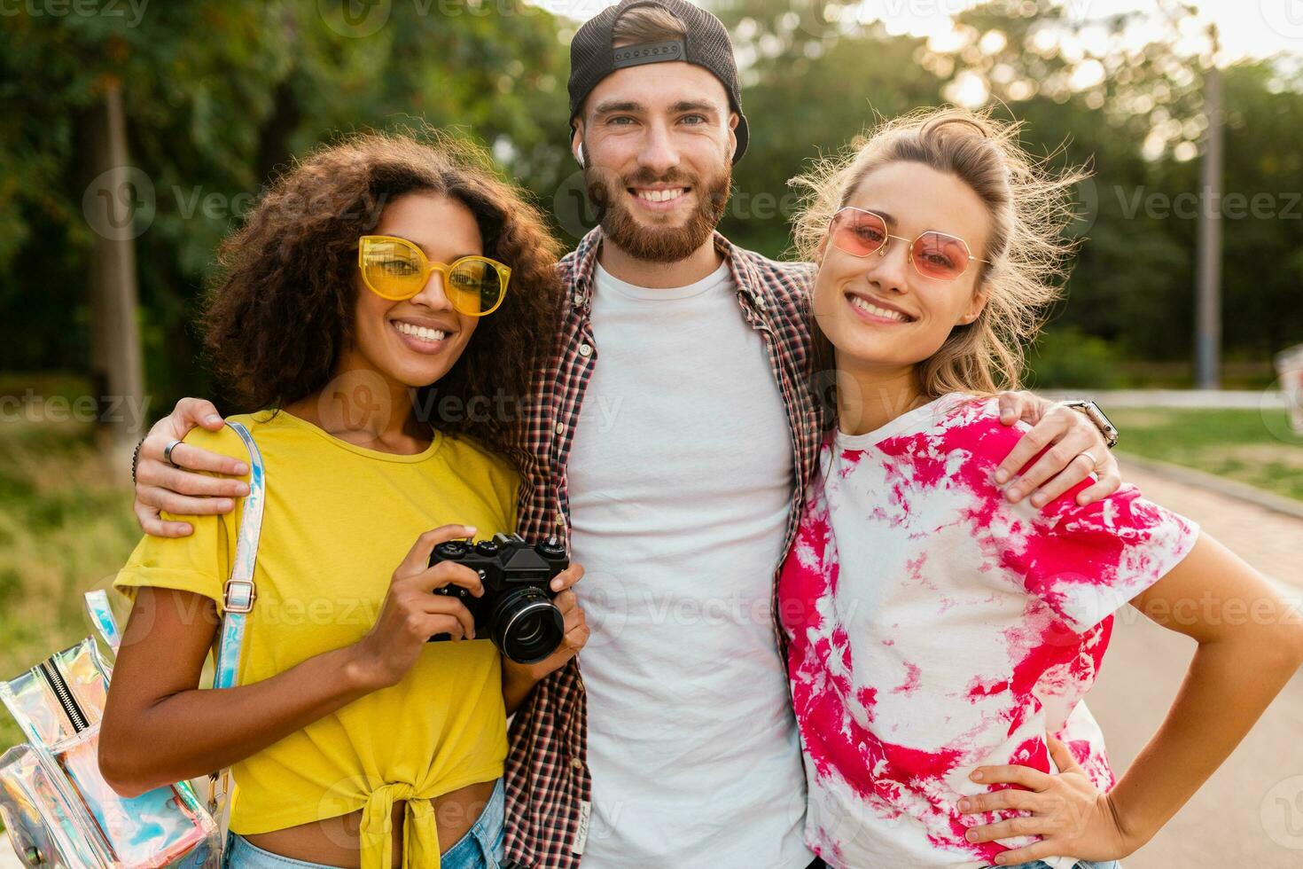 happy young company of emotional smiling friends walking in park photo