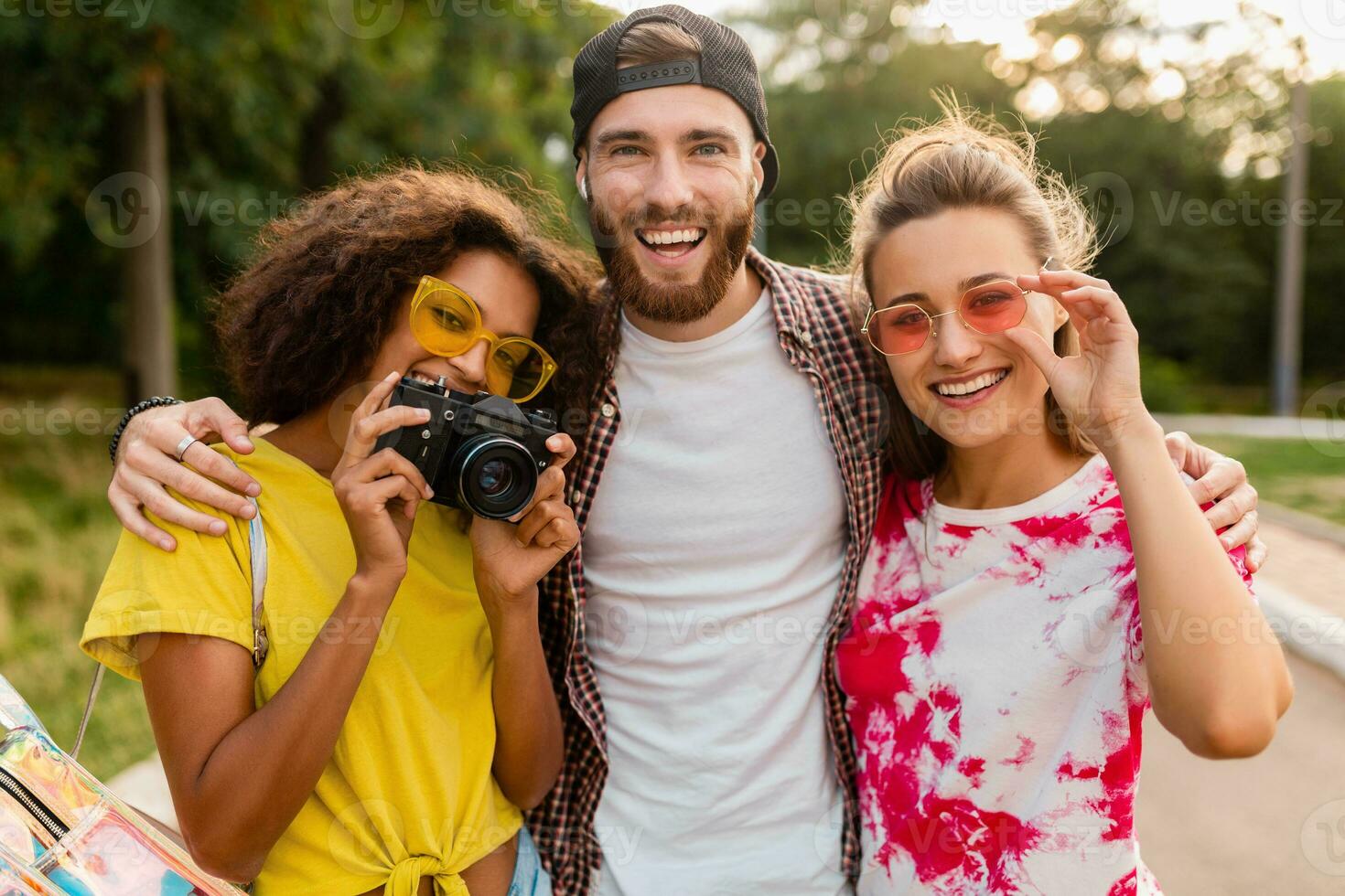 happy young company of emotional smiling friends walking in park photo