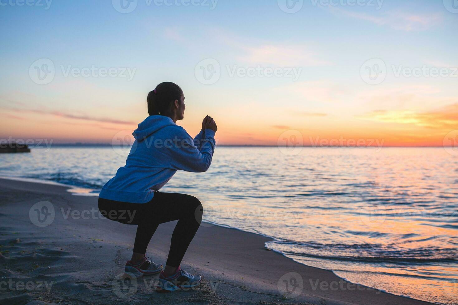 joven mujer haciendo deporte ejercicios en amanecer playa en Mañana foto