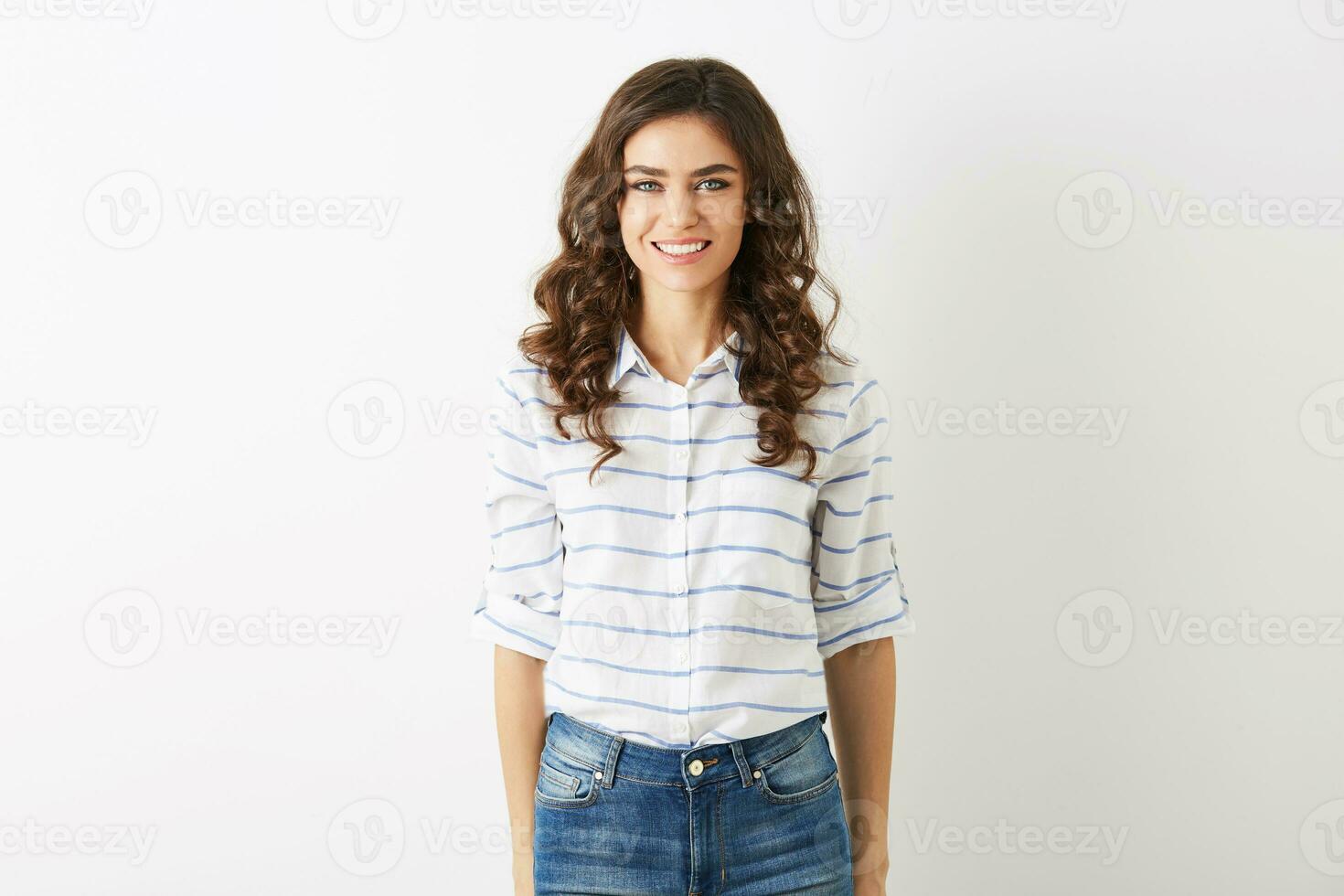 attractive young woman dressed in casual student style, shirt and jeans, curly hair, smiling, looking in camera, beautiful model isolated on white studio background, white teeth, pretty face photo