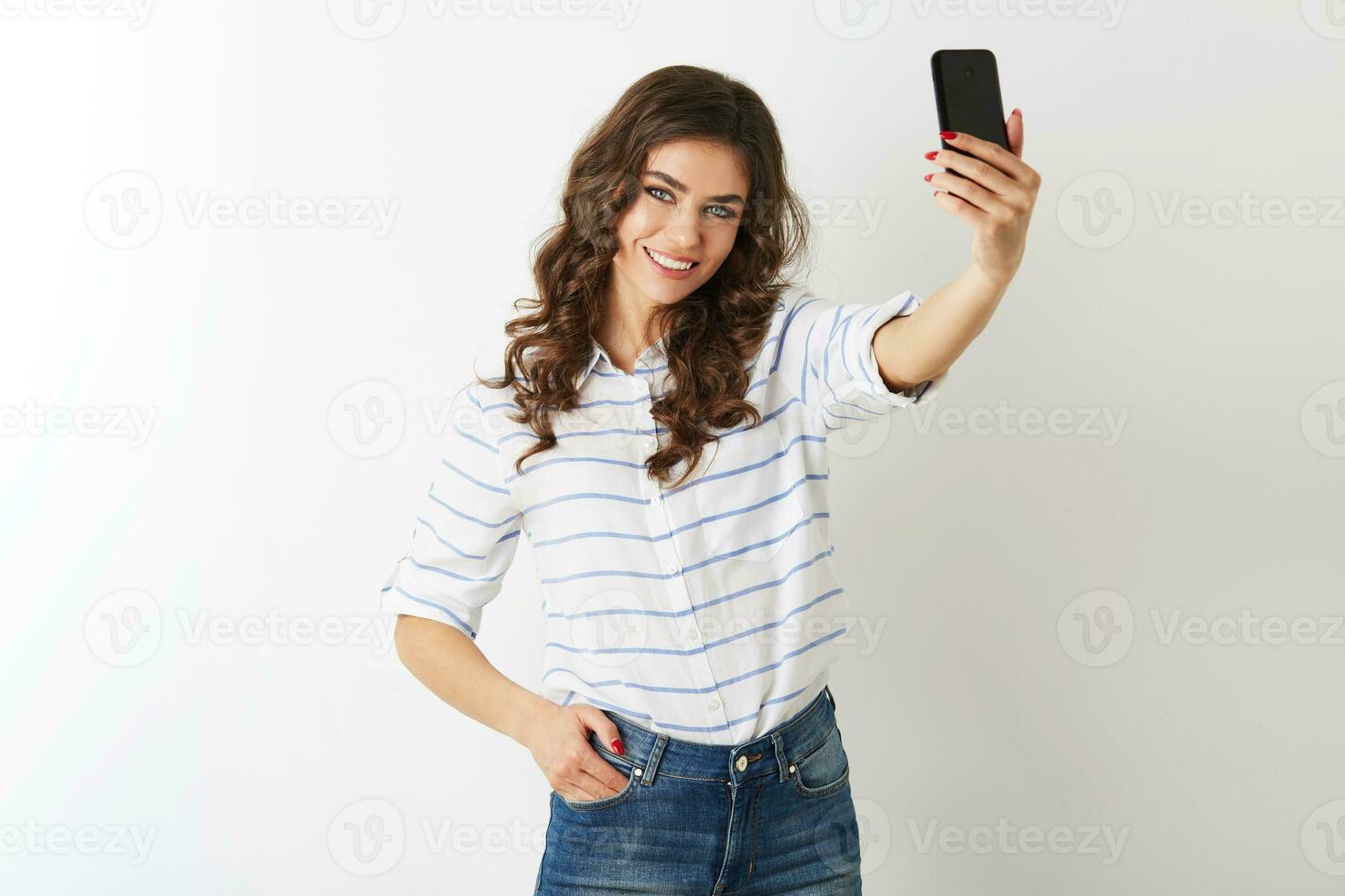 beautiful woman making selfie photo on mobile phone, smiling, happy, islolated, curly hair, positive mood, looking in camera, attractive model posing