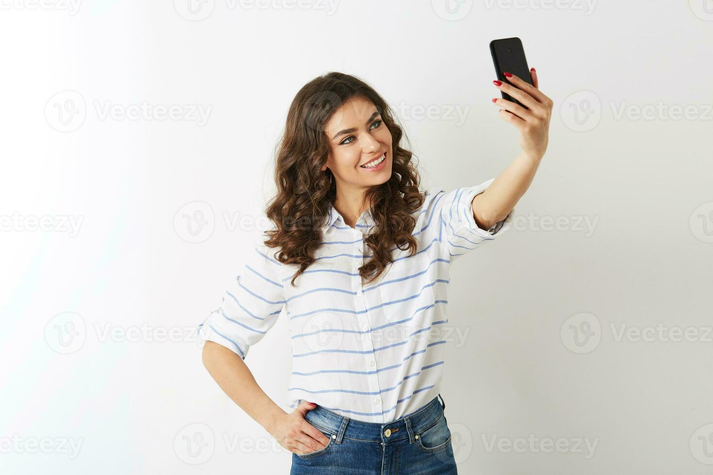 beautiful woman making selfie photo on mobile phone, smiling, happy, islolated, curly hair, positive mood, looking in camera, attractive model posing