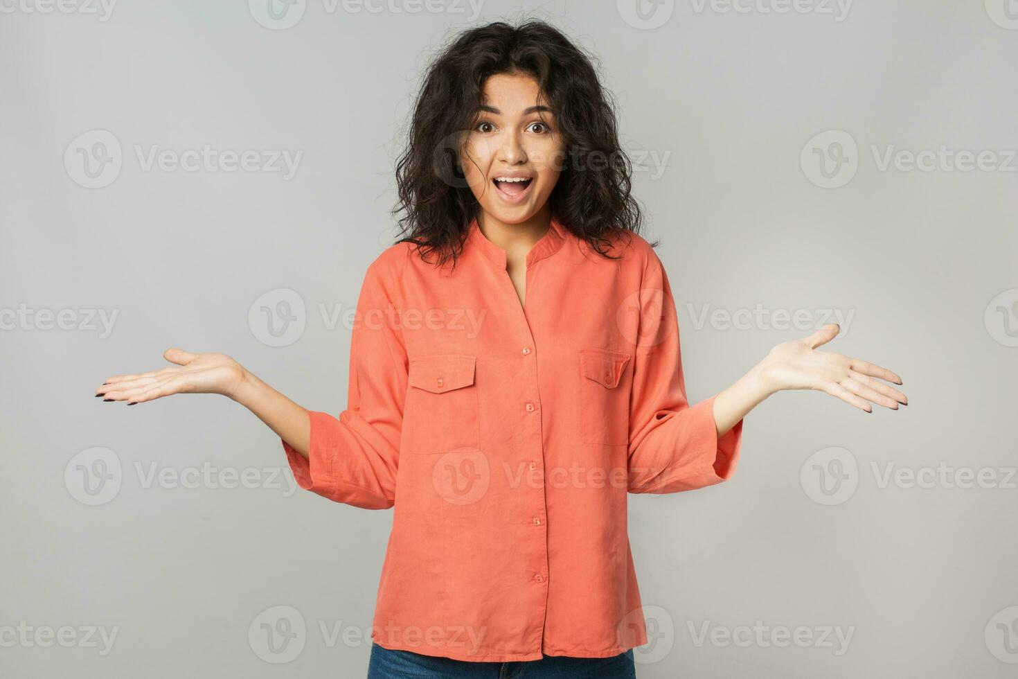portrait of young happy pretty brunette woman in orange shirt, surprised face expression, shocked emotion, funny, holding hands up, summer style, natural look, looking in camera, mixed race, isolated photo