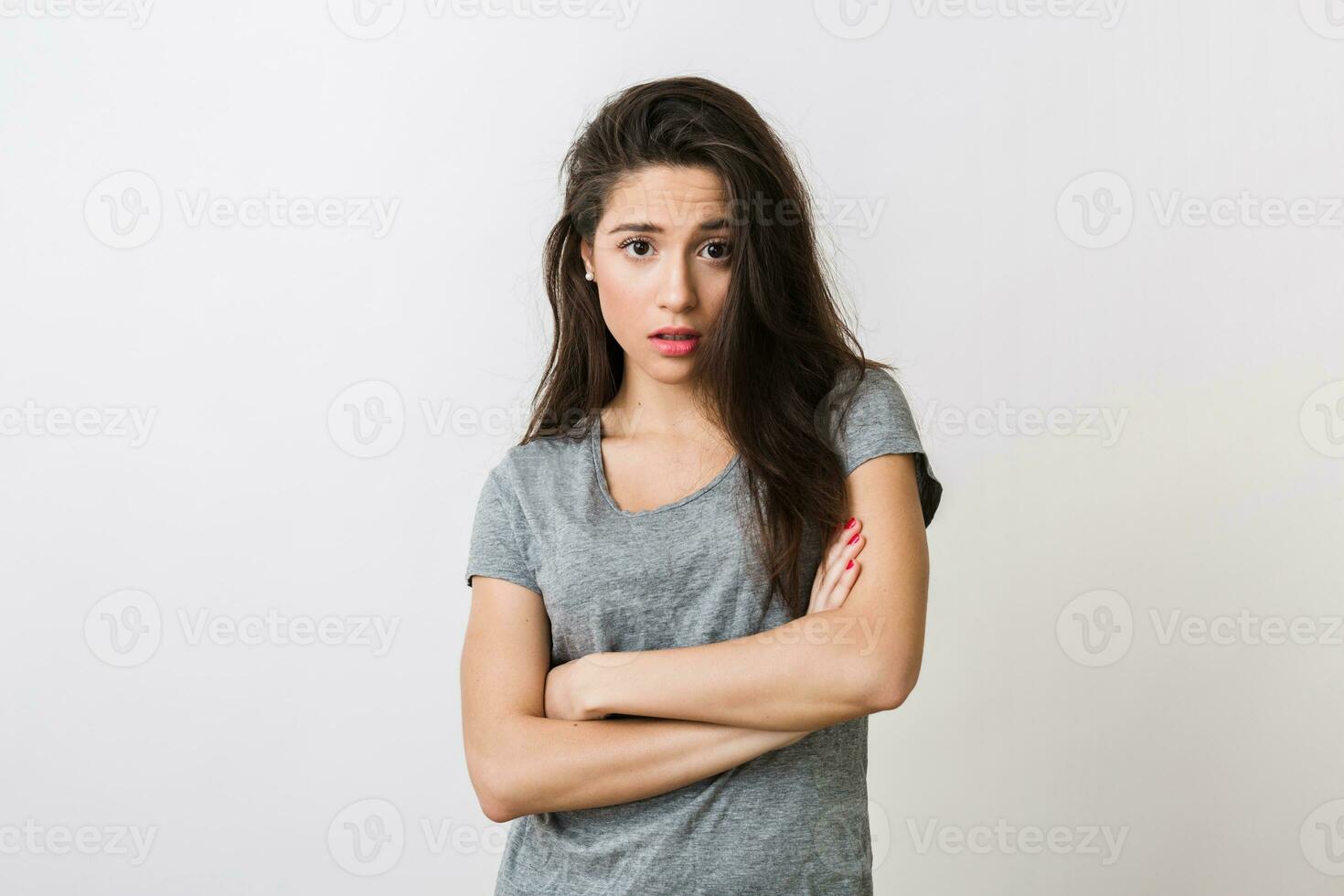 young pretty hipster woman with surprised expression of face, shocked, grey t-shirt, posing on white studio background, isolated, long hair, natural look photo