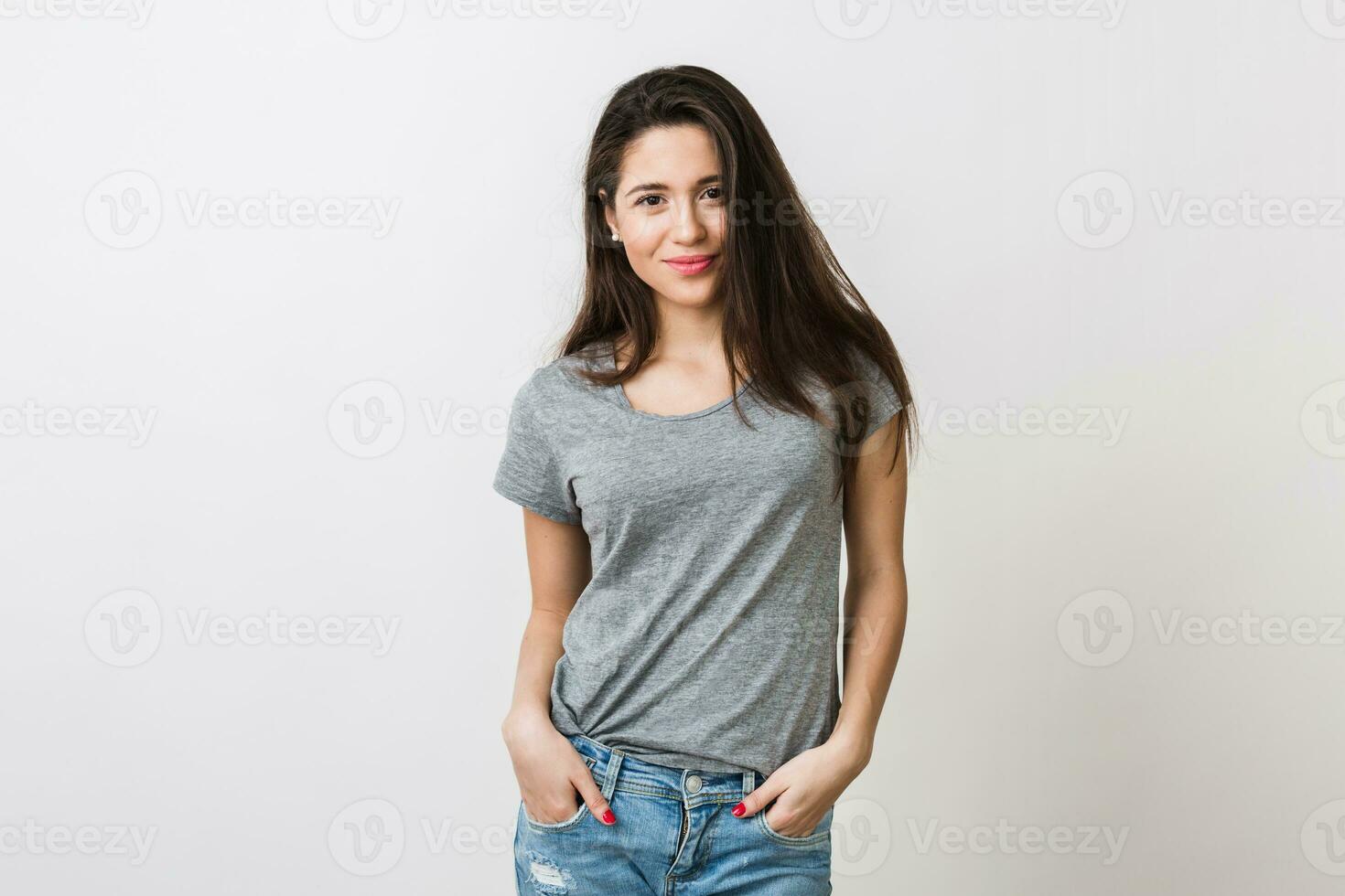 portrait of stylish young pretty woman smiling in grey t-shirt on white studio background, isolated, natural look, long brown hair, jeans, sexy, casual style photo