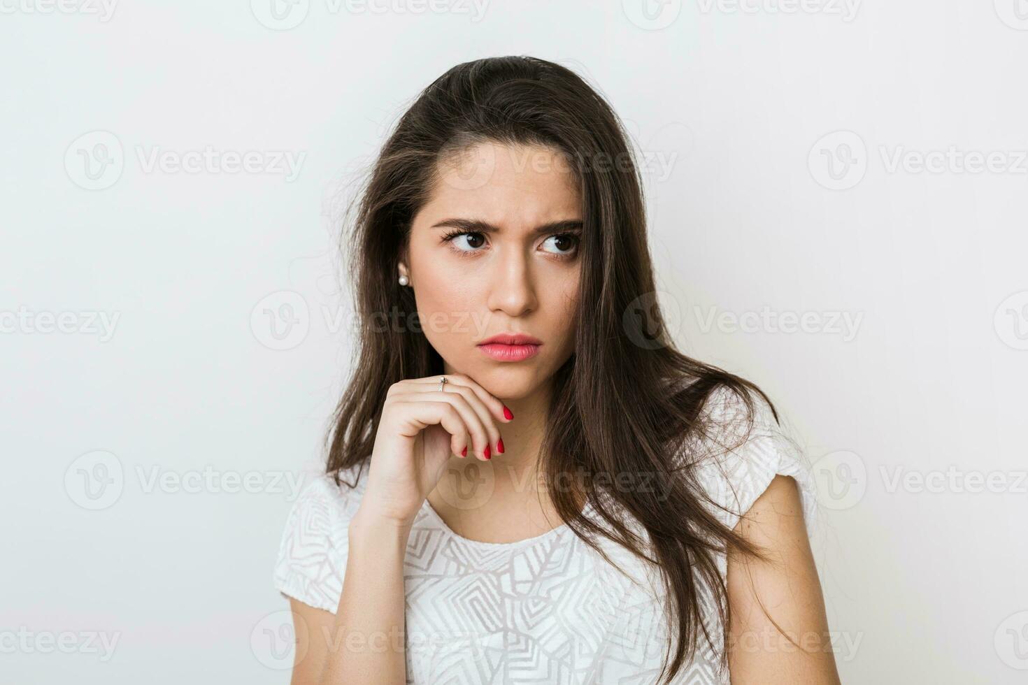 close-up portrait of young thinking woman in white blouse, frowning, holding hand at her face, looking aside, serious face expression, having a problem isolated photo