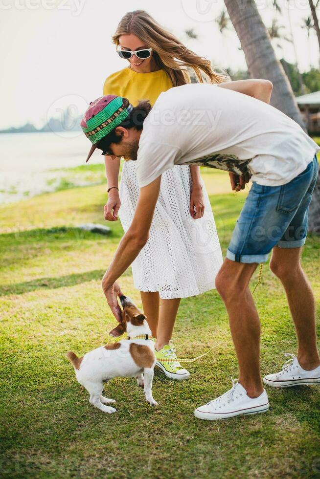 young stylish hipster couple in love holding a dog at the tropical park photo