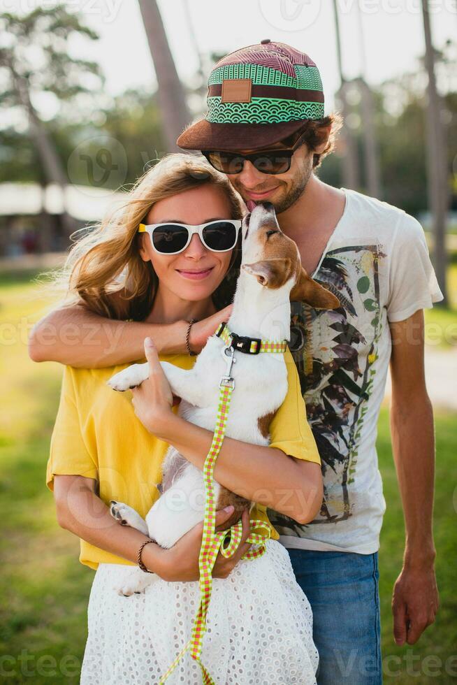 young stylish hipster couple in love holding a dog at the tropical park photo