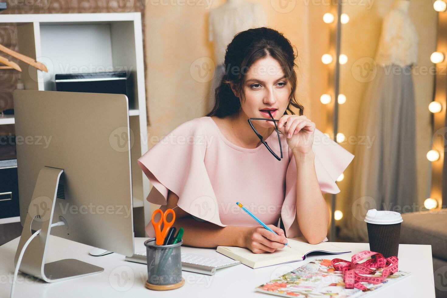 woman in pink luxury dress, summer trend, fashion designer working at office on computer photo