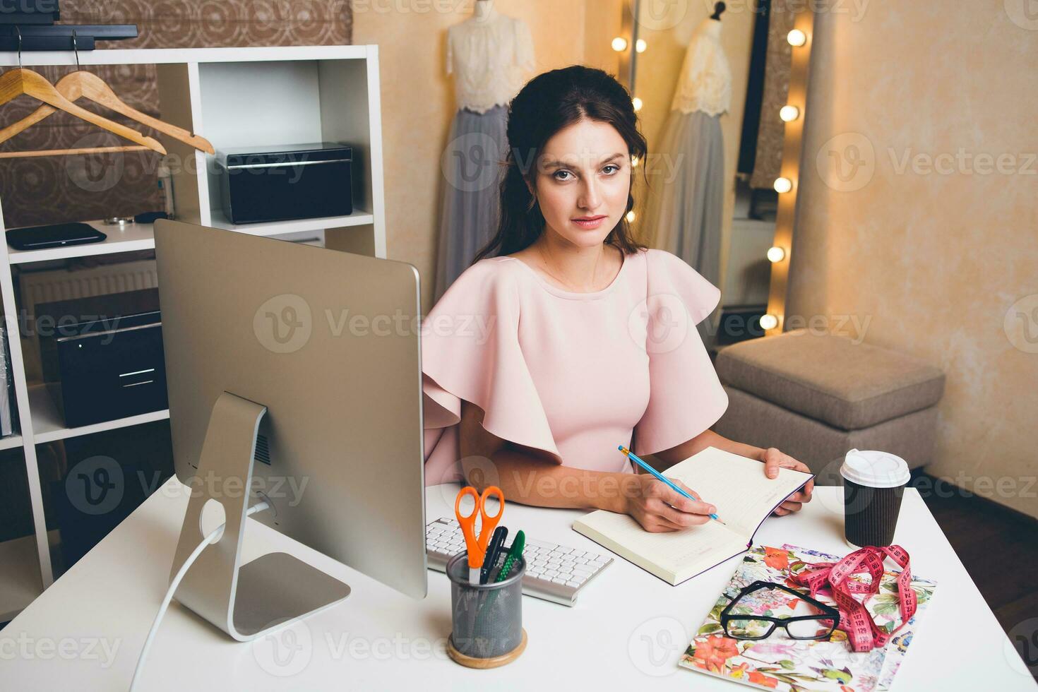 woman in pink luxury dress, summer trend, fashion designer working at office on computer photo