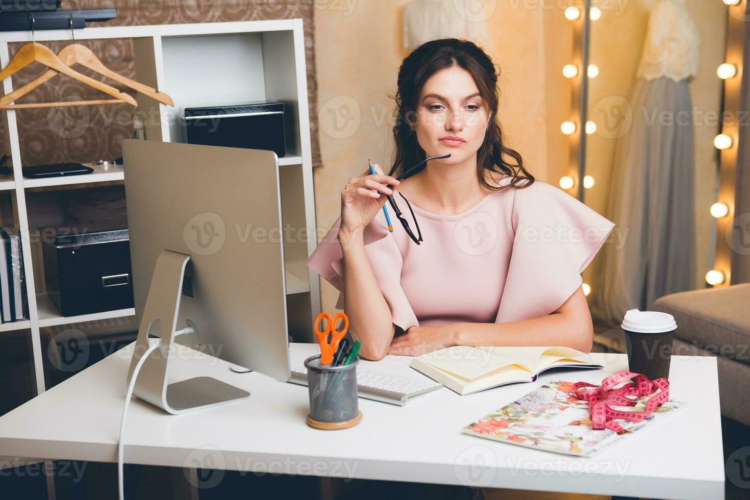 woman in pink luxury dress, summer trend, fashion designer working at office on computer photo