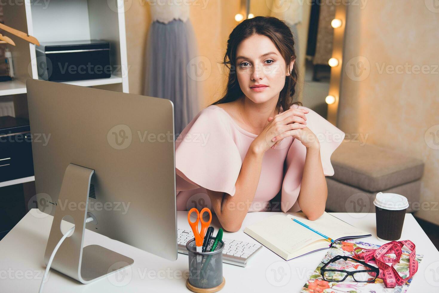 woman in pink luxury dress, summer trend, fashion designer working at office on computer photo
