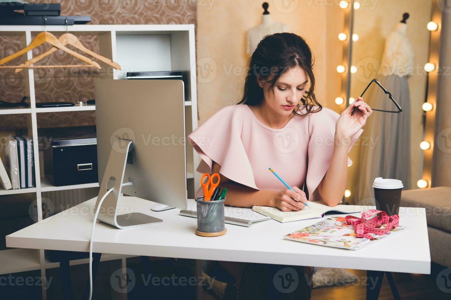 woman in pink luxury dress, summer trend, fashion designer working at office on computer photo
