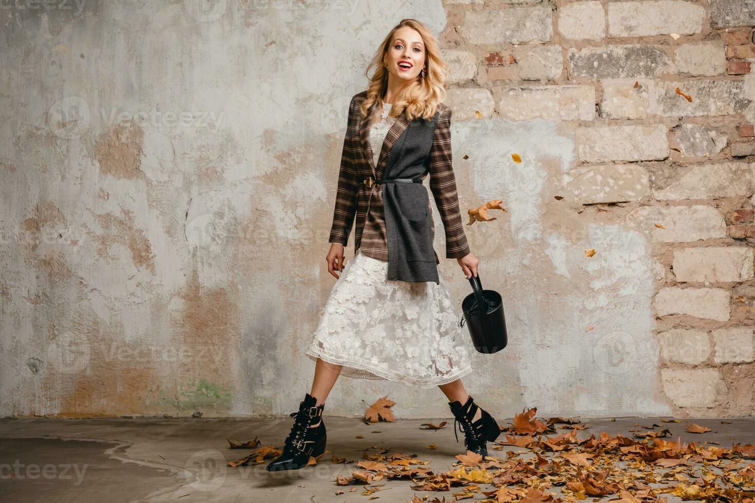 attractive stylish blonde woman in checkered jacket coat walking, autumn fashion trend photo