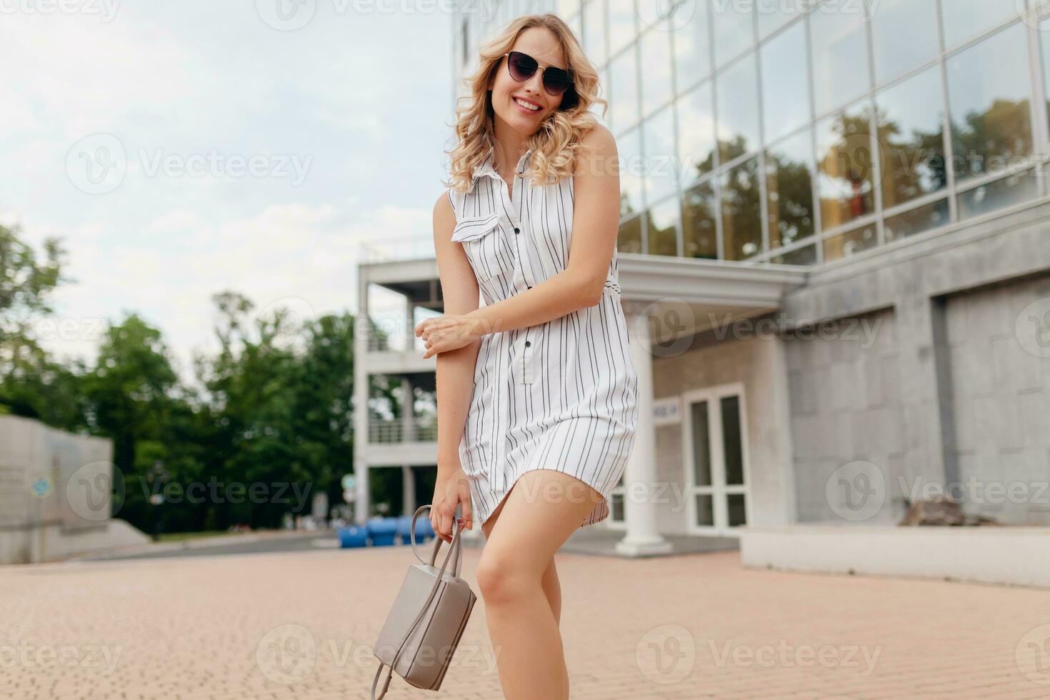 young attractive stylish elegant woman with blond hair walking in city street photo
