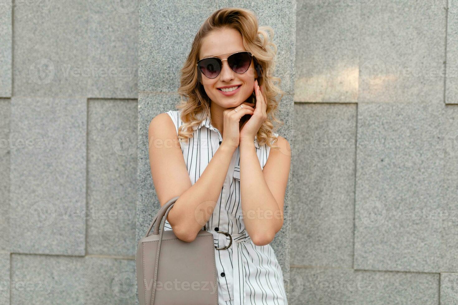 close-up portrait of young attractive stylish blonde woman in city street in summer fashion style photo