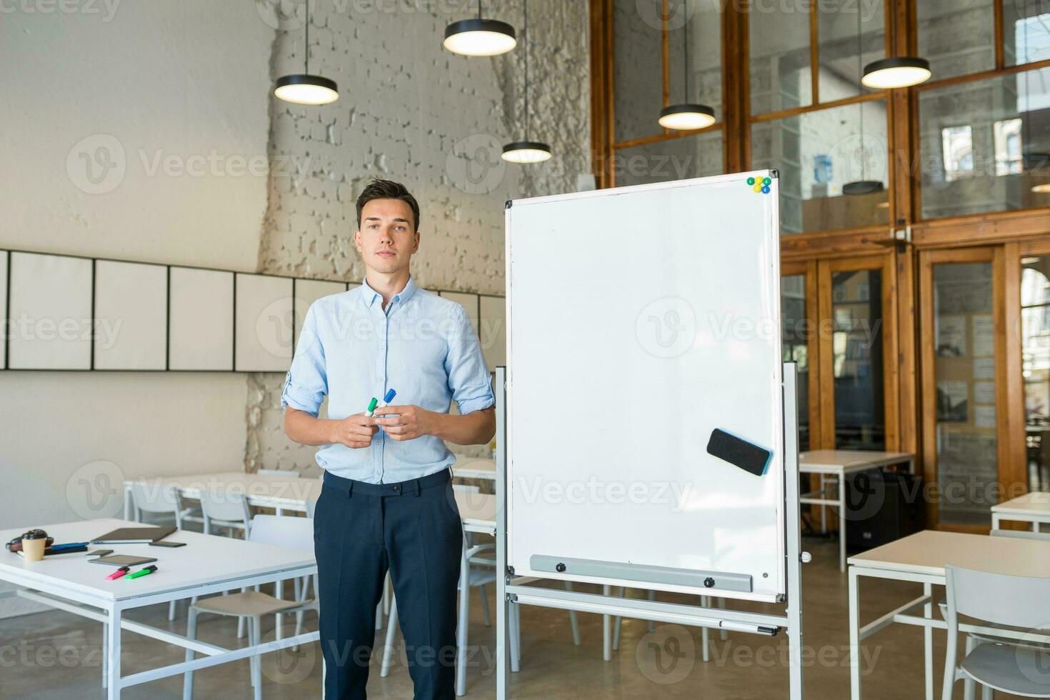 confident young handsome smiling man standing at empty white board with marker photo