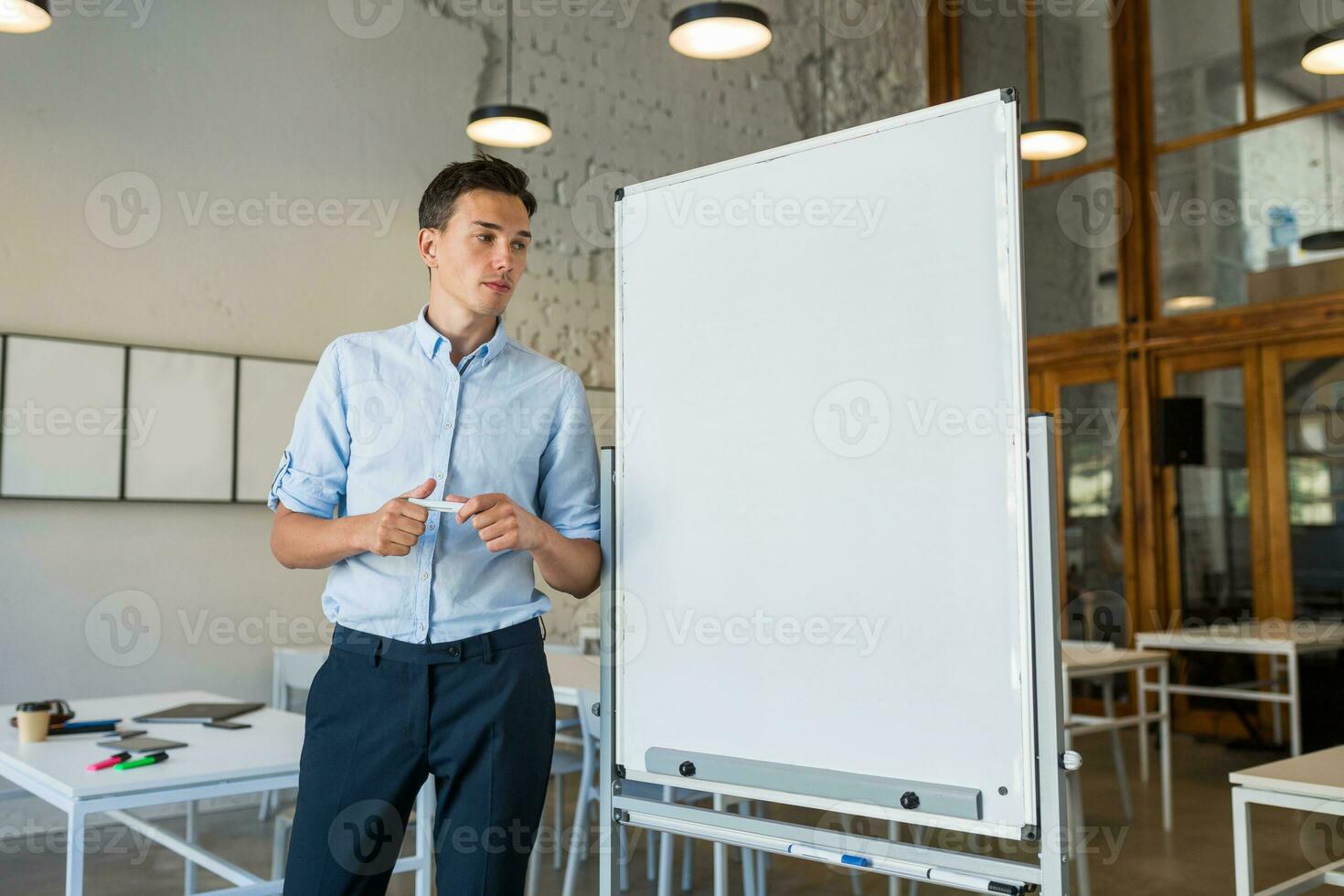 confidente joven hermoso sonriente hombre en pie a vacío blanco tablero con marcador foto