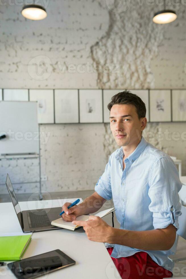 contento joven confidente hombre trabajando en ordenador portátil foto