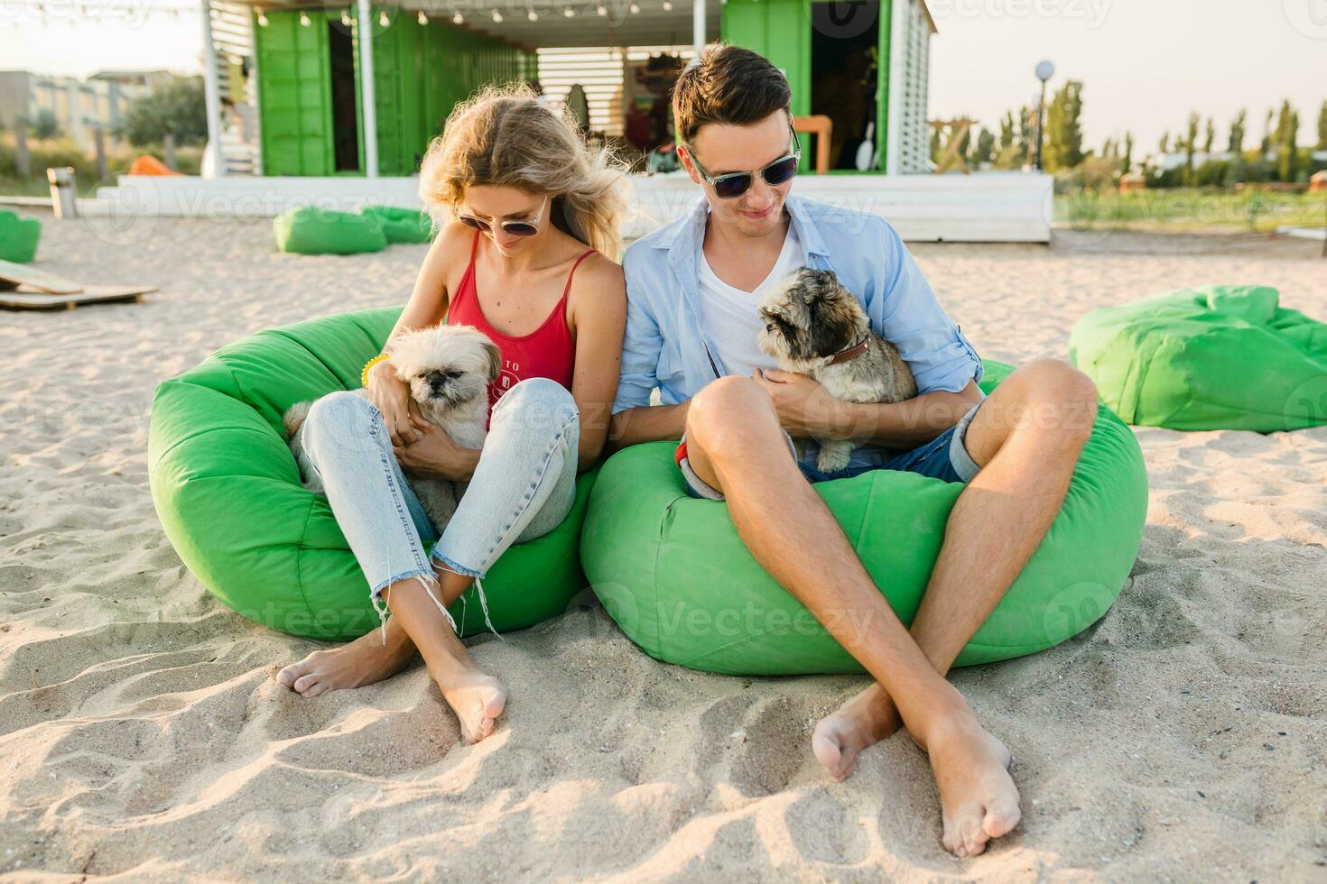 young attractive smiling couple having fun on beach playing with dogs photo