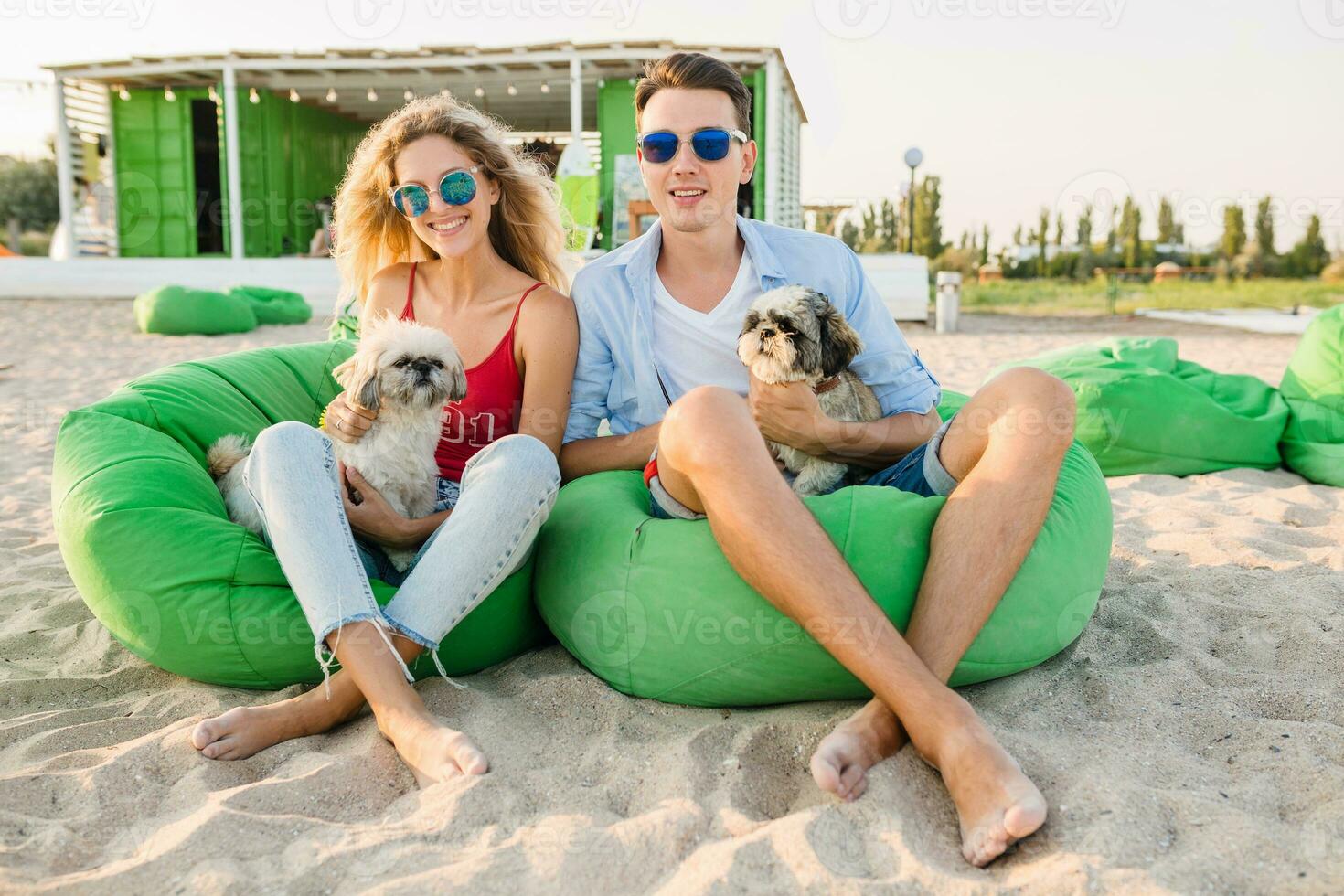 young attractive smiling couple having fun on beach playing with dogs photo