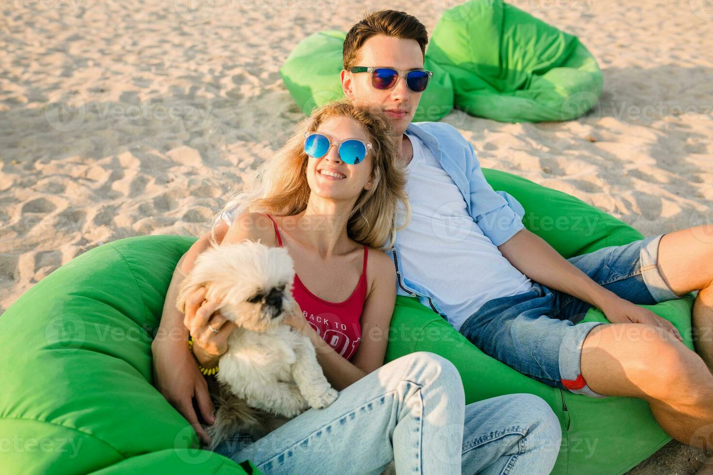 joven atractivo sonriente Pareja teniendo divertido en playa jugando con perros foto