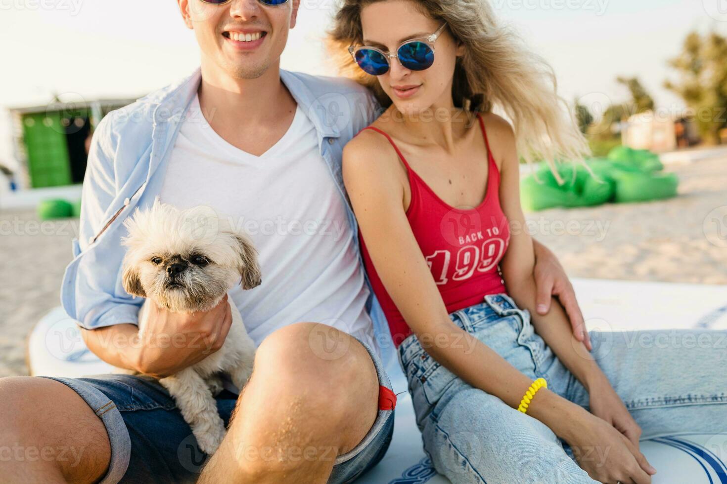 young attractive smiling couple having fun on beach playing with dogs photo