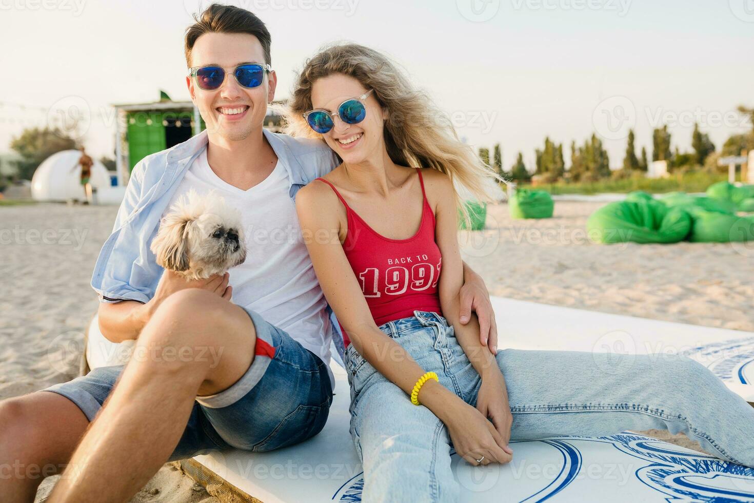 young attractive smiling couple having fun on beach playing with dogs photo