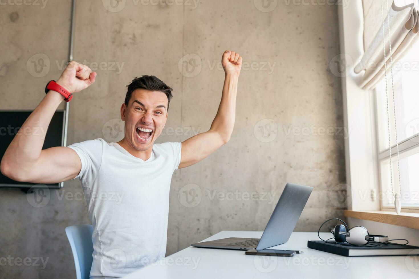 joven hermoso hombre en casual atuendo sentado a mesa trabajando en computadora portátil, mecanografía, persona de libre dedicación a hogar foto