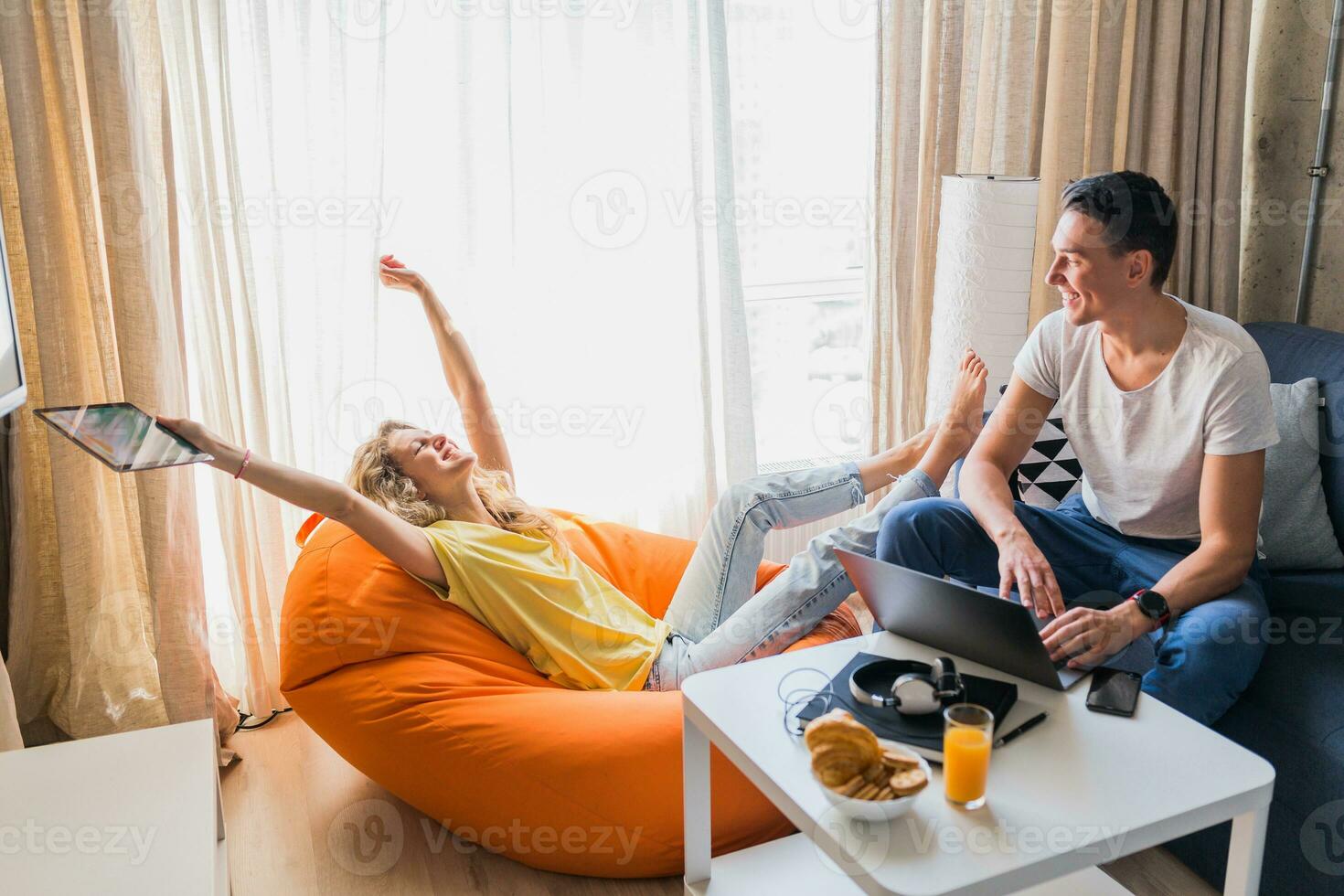 young man and woman in love sitting at home working online photo