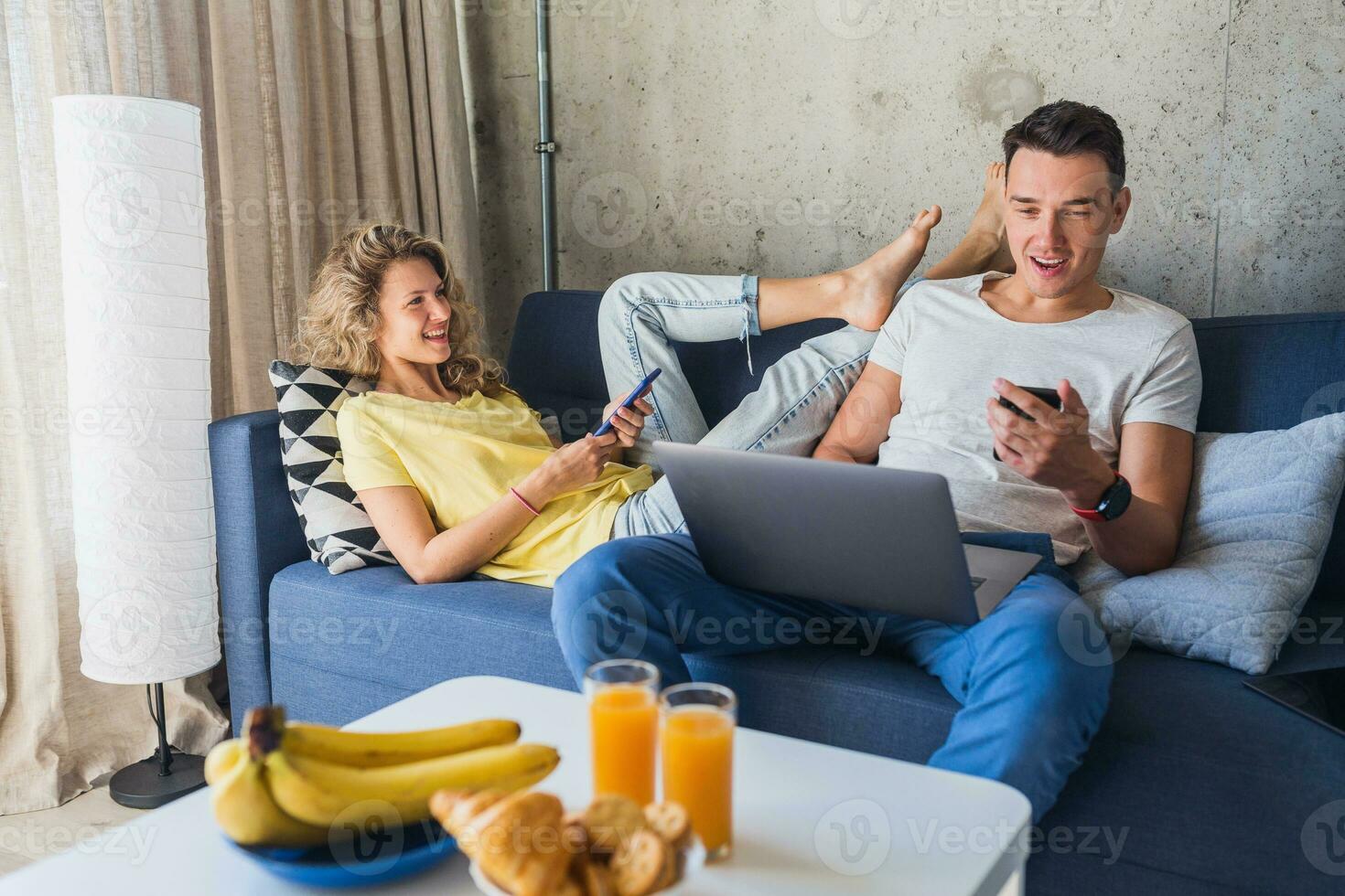 young man and woman in love sitting at home working online photo