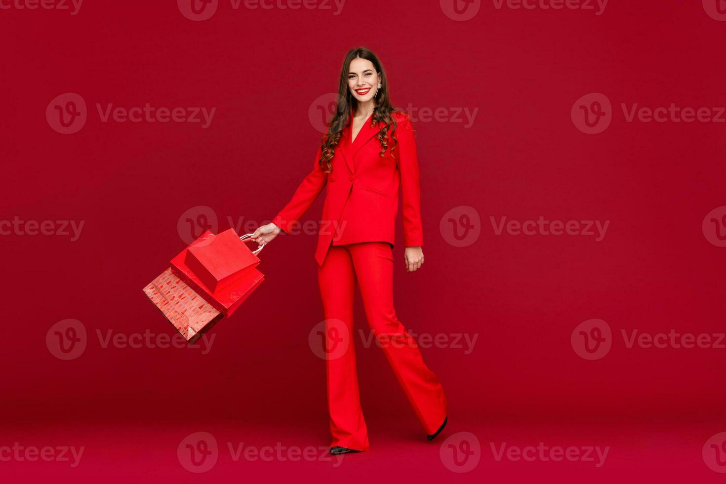 attractive woman in red with shopping bags sale on red background photo