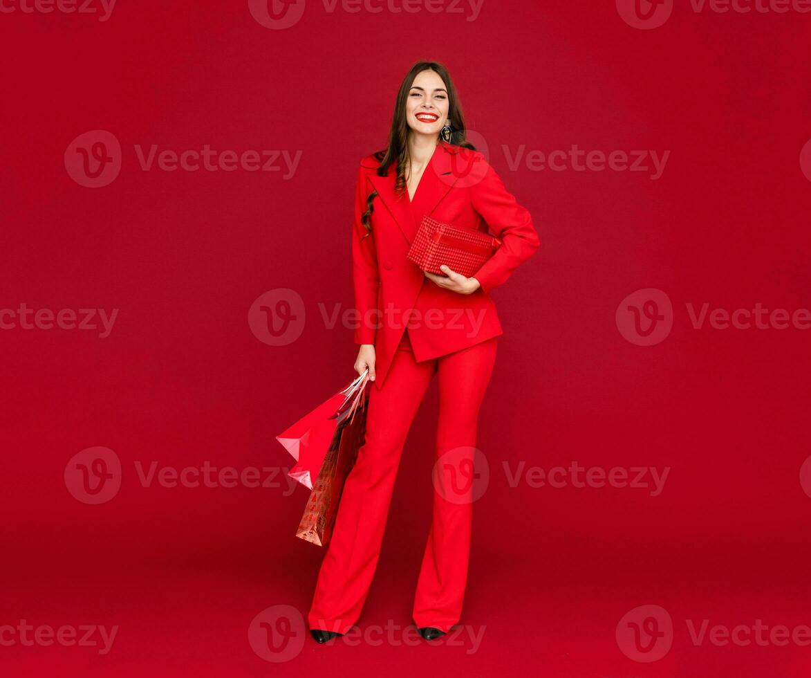 attractive woman in red with shopping bags sale on red background photo