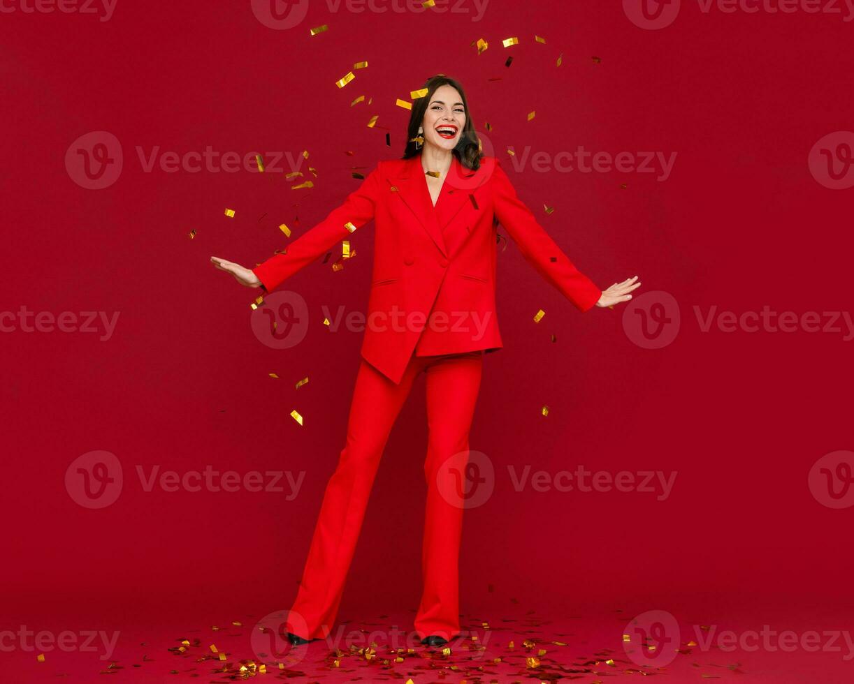 attractive woman celebrating Christmas on red background in confetti photo