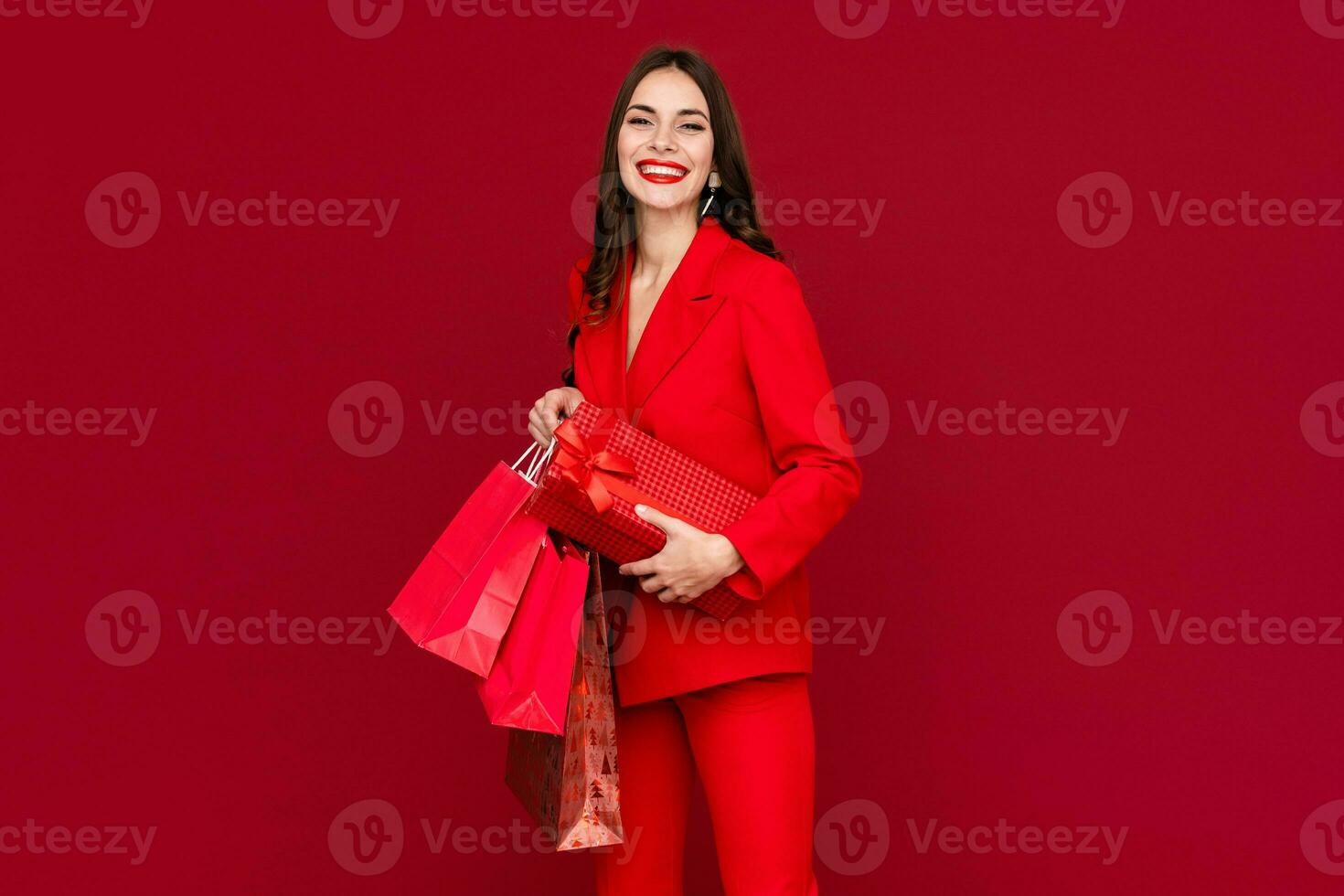 attractive woman in red with shopping bags sale on red background photo