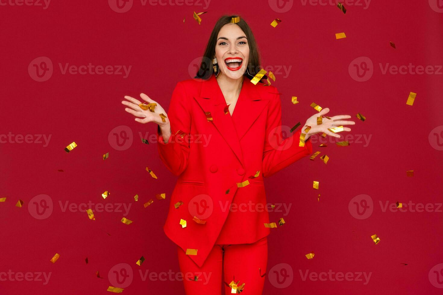 attractive woman celebrating Christmas on red background in confetti photo